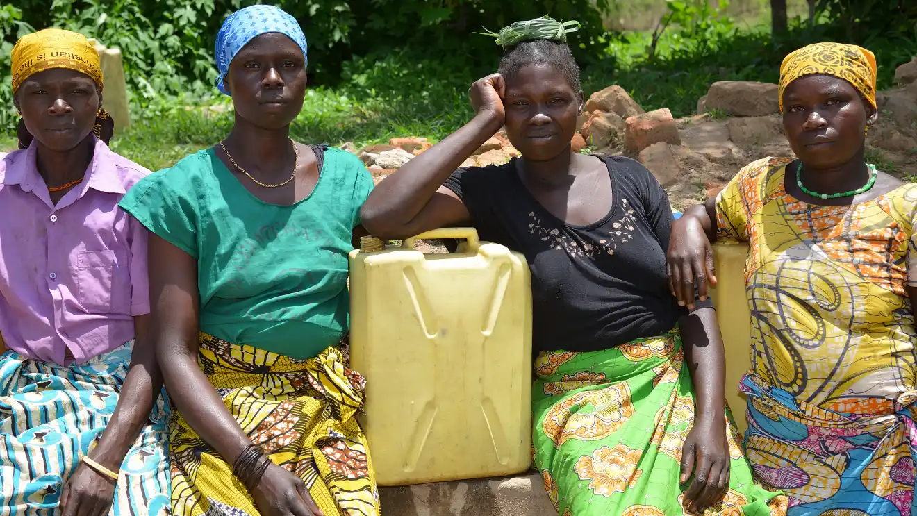 Vier Afrikanerinnen mit Wasserkanistern beim Wasser holen